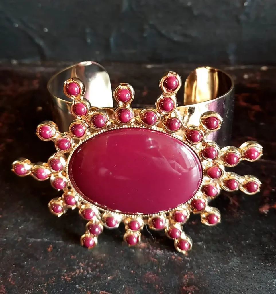 Cuff piece adorned with stunning 'ruby’ red stone, surrounded with smaller stones.